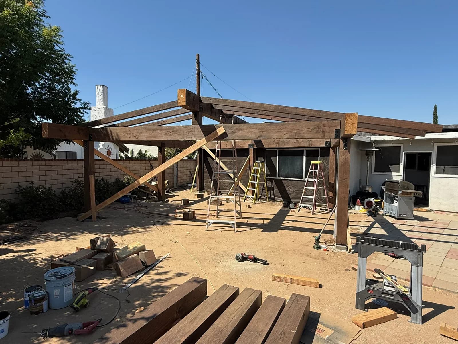 Backyard patio cover during construction, showing the bare post and beam frame.
